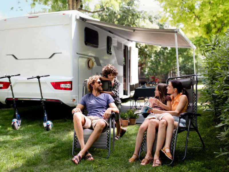 Famille profitant du grand air devant son camping car au camping