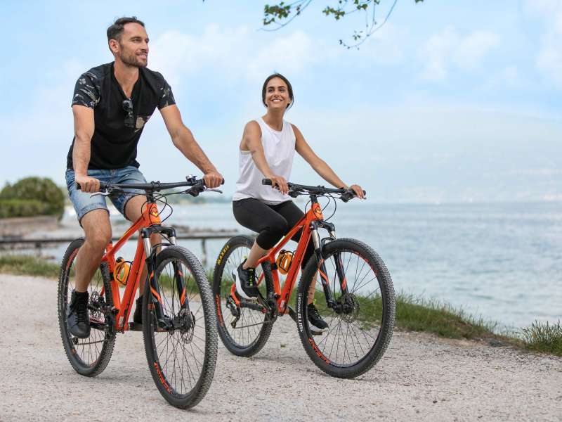 Couple qui pédale au bord du lac de Garde avec des vélos de location
